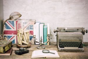 a desk with an old typewriter camera and book